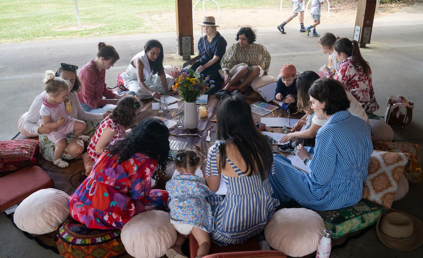 A group of women sitting together outdoors, laughing candidly in natural sunlight